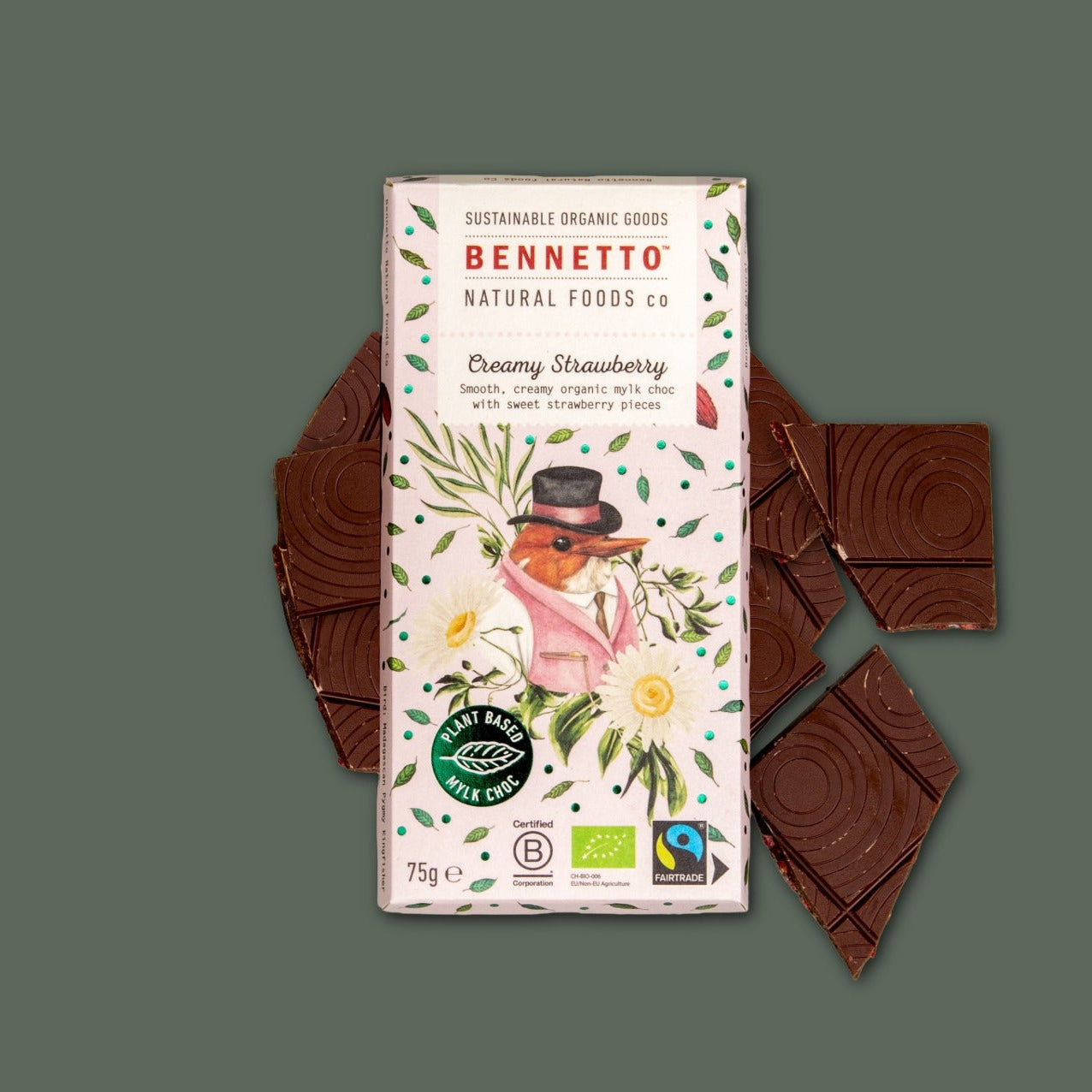A Bennetto Creamy Strawberry chocolate bar package is centered on a muted green background, flanked by pieces of dark chocolate.