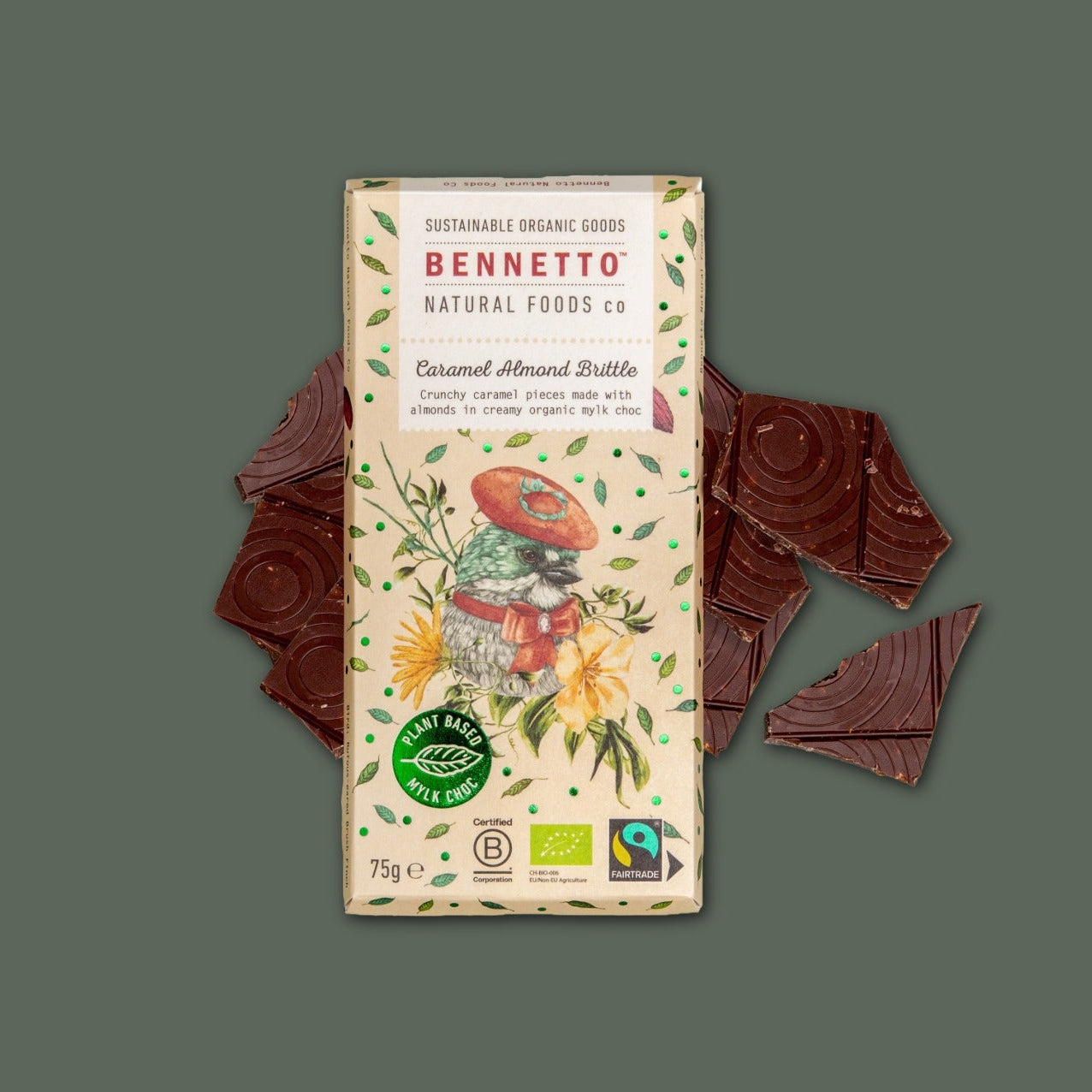 A bar of Bennetto Caramel Almond Brittle chocolate is centered on a muted green background, with several chocolate pieces placed behind and beside the package.
